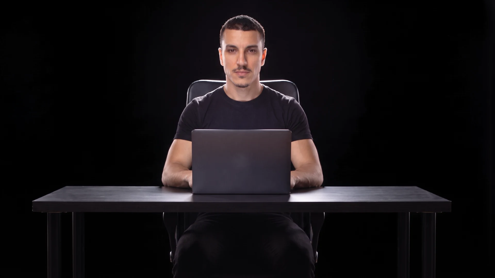 Mouncef Tamda seated at the desk in the dark.